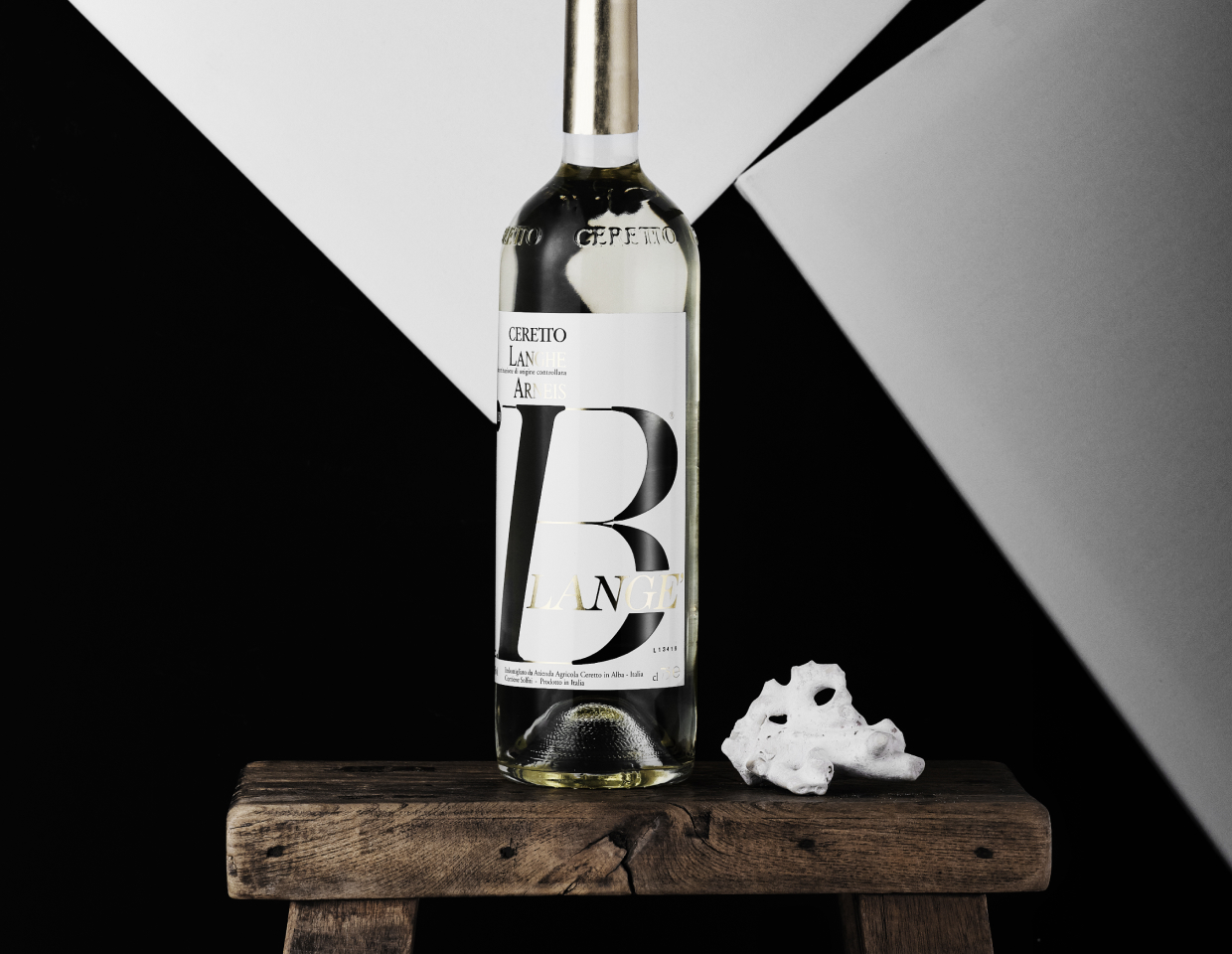 Ceretto Arneis Blange bottle on wooden table in from of a geometric wallpaper