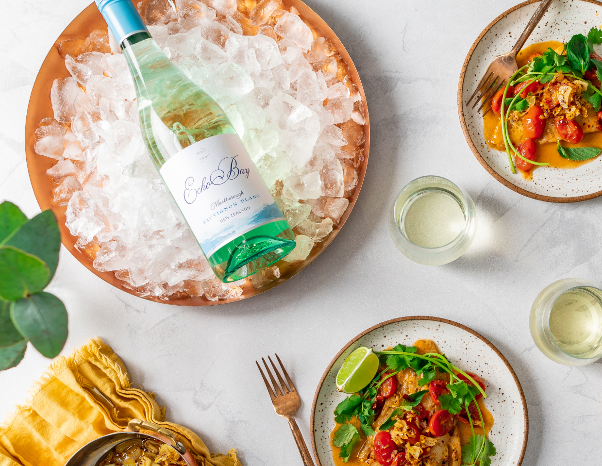 Bottle of Echo Bay Sauvignon Blanc on ice on a table set for dinner.