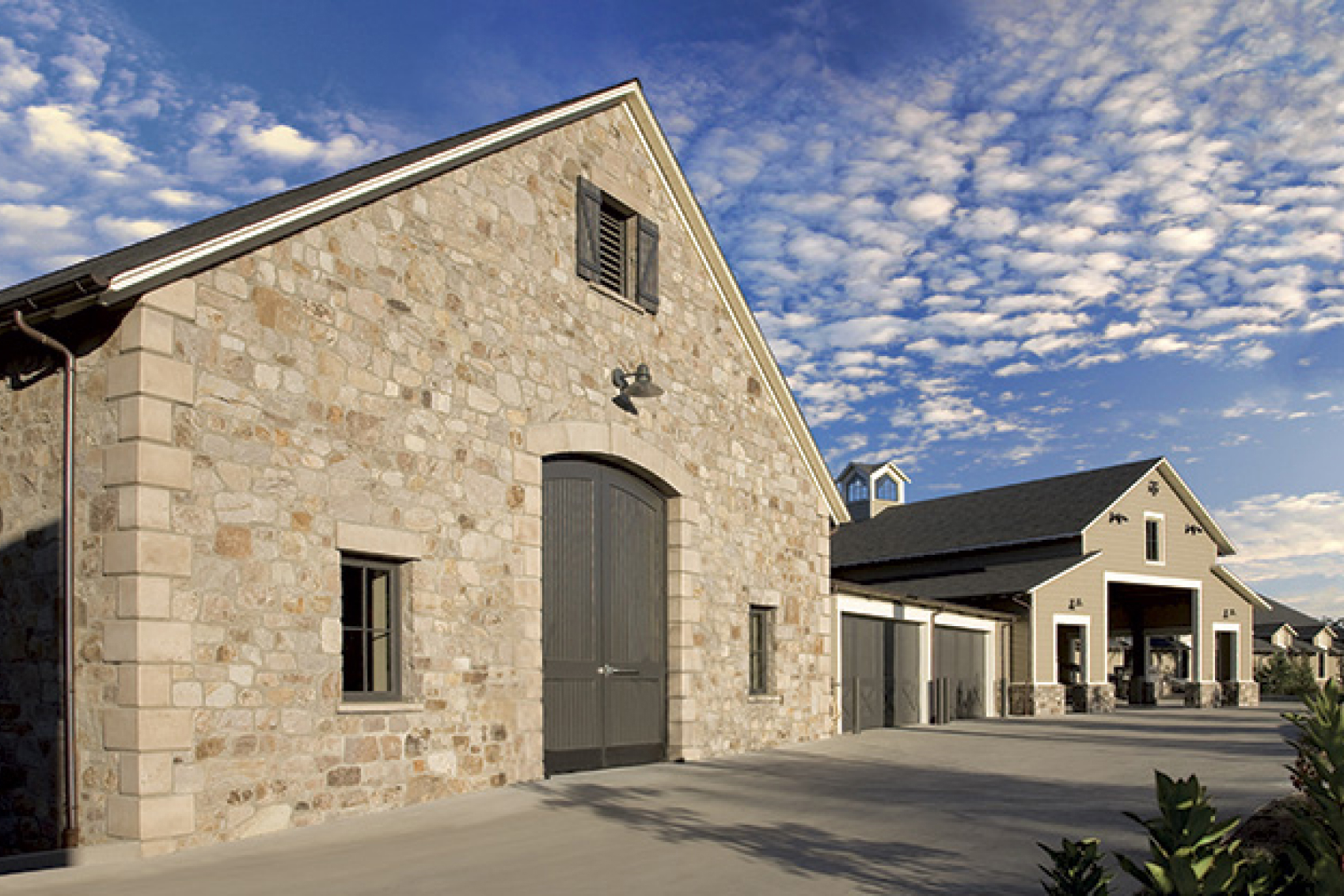 The beautiful winemaking out-buildings of Trinchero Napa Valley winery in front of a bright blue sky spotted with clouds