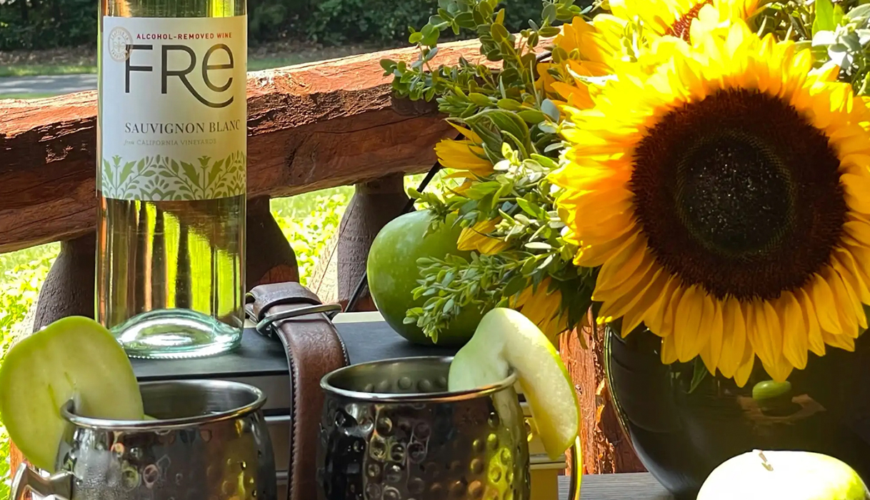 FRE fall mule made with FRE sauvignon blanc next to a beautiful sunflower and apples on a porch.