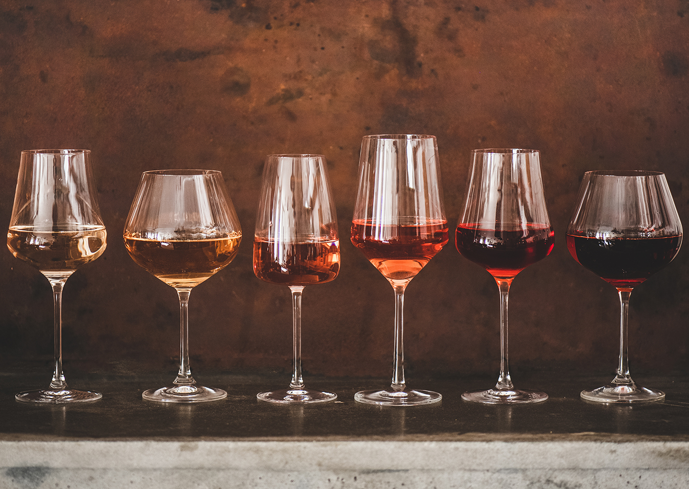 lineup of multiple types of wines in different glasses