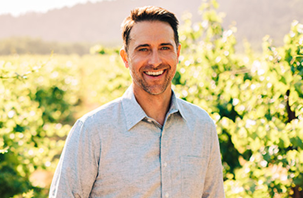 bravium and outlier winemaker derek rohlffs outside in the vineyard wearing a blue button down shirt