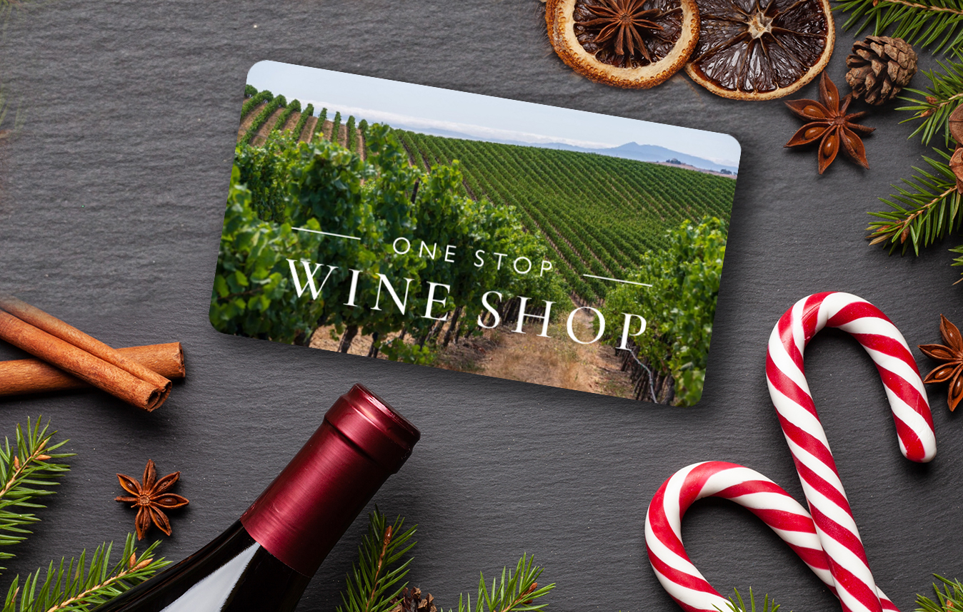 One Stop Wine Shop gift card laying flat on a table by a bottle of wine and candy canes