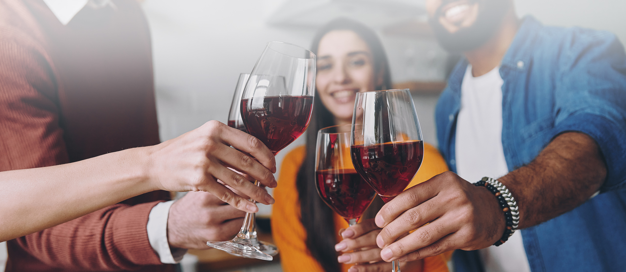 group of people clinking red wine glasses and smiling