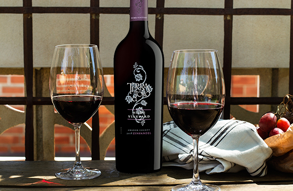 bottle of Terra d'Oro home vineyard zinfandel with full wine glasses on a table outdoors