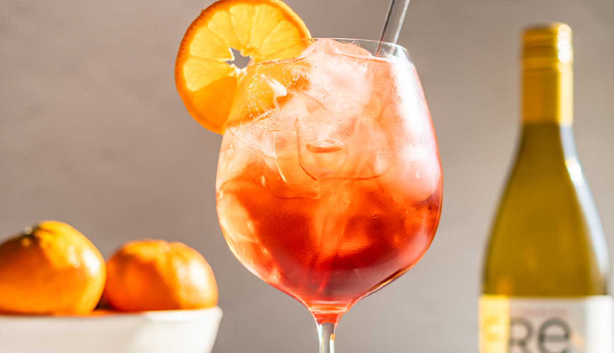 a classic Italian spritz mocktail in a big wine glass with a wheel of orange made with FRE alcohol-removed chardonnay