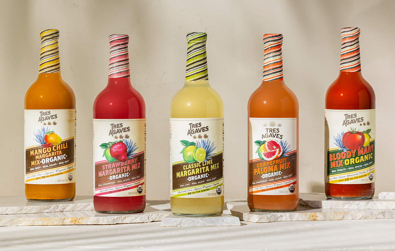 lineup of bottles of Tres Agaves mixers with a taupe background