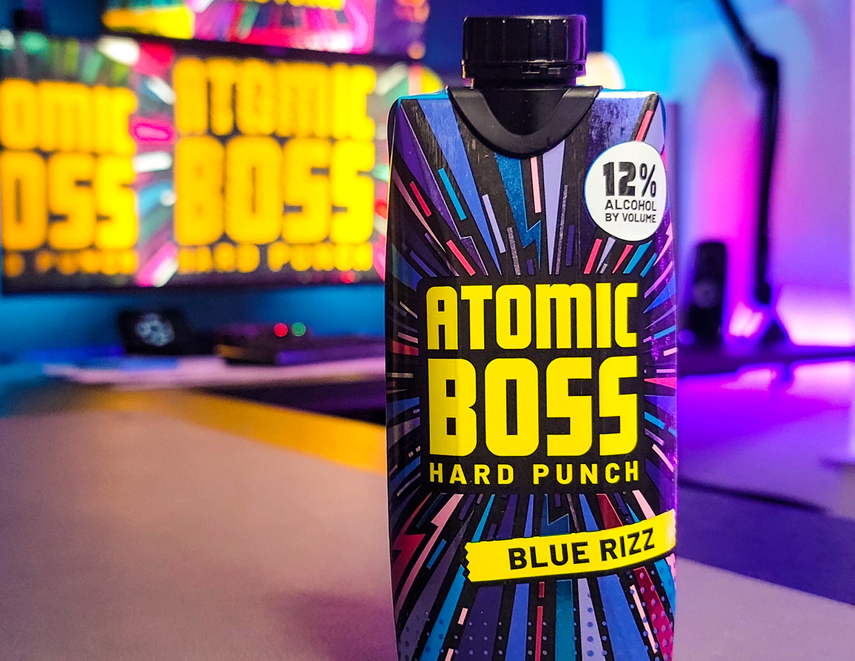 box of Atomic Boss Hard Punch, blue rizz flavor on a desktop with screens in the background.