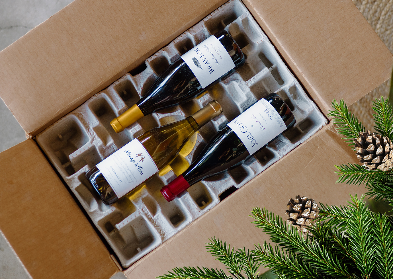 unboxing an expertly packed One Stop Wine Shop wine club shipment, with pinecones and greenery in the corner
