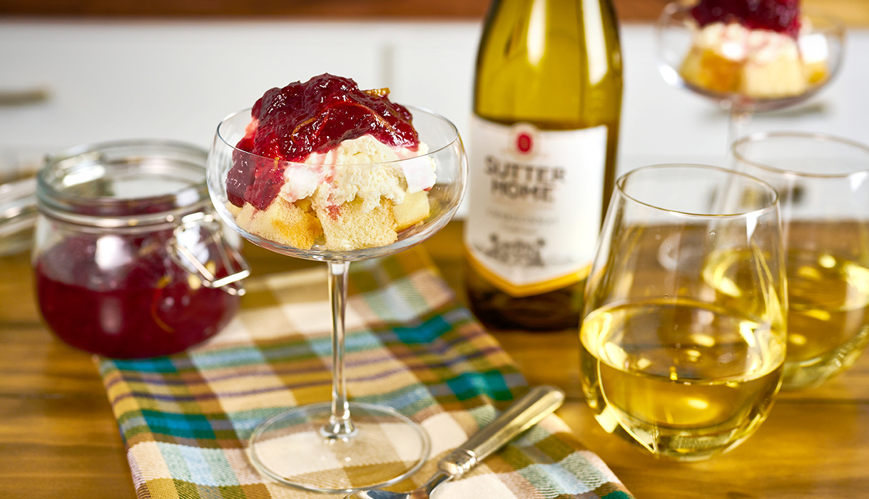 Cranberry poundcake parfait in a beautiful champagne glass next to a bottle of sutter home chardonnay