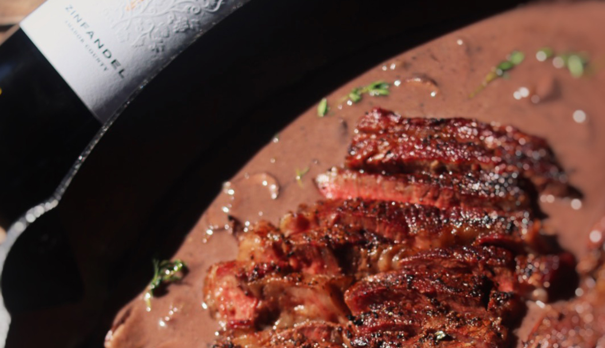 Ribeye with zinfandel mushroom sauce in a skillet next to a bottle of Terra d'Oro zinfandel