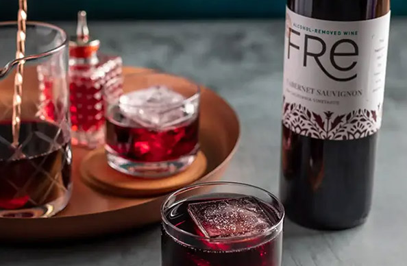 a glass of cabernet manhattan mocktail made with FRE alcohol-removed cabernet sauvignon next to a gold platter with cocktail making accessories on it. Get this mocktail recipe and more from One Stop Wine Shop.