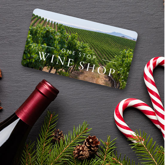 a One Stop Wine Shop virtual gift card lying flat next to a bottle of wine, some candy canes, and pine tree sprigs and pine cones. Shop gift cards.