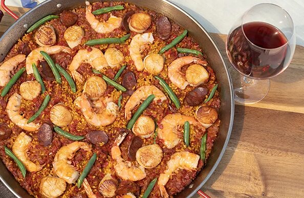 http://a%20pan%20of%20Spanish%20paella%20bursting%20with%20shrimp%20and%20chorizo,%20next%20to%20a%20glass%20of%20red%20wine%20on%20a%20wooden%20table.%20Try%20this%20delicious%20recipe.