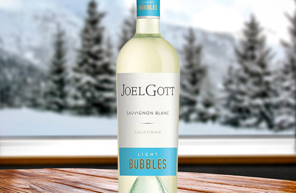 Bottle of new Joel Gott Sauvignon Blanc light bubbles in front of a snowy scene.