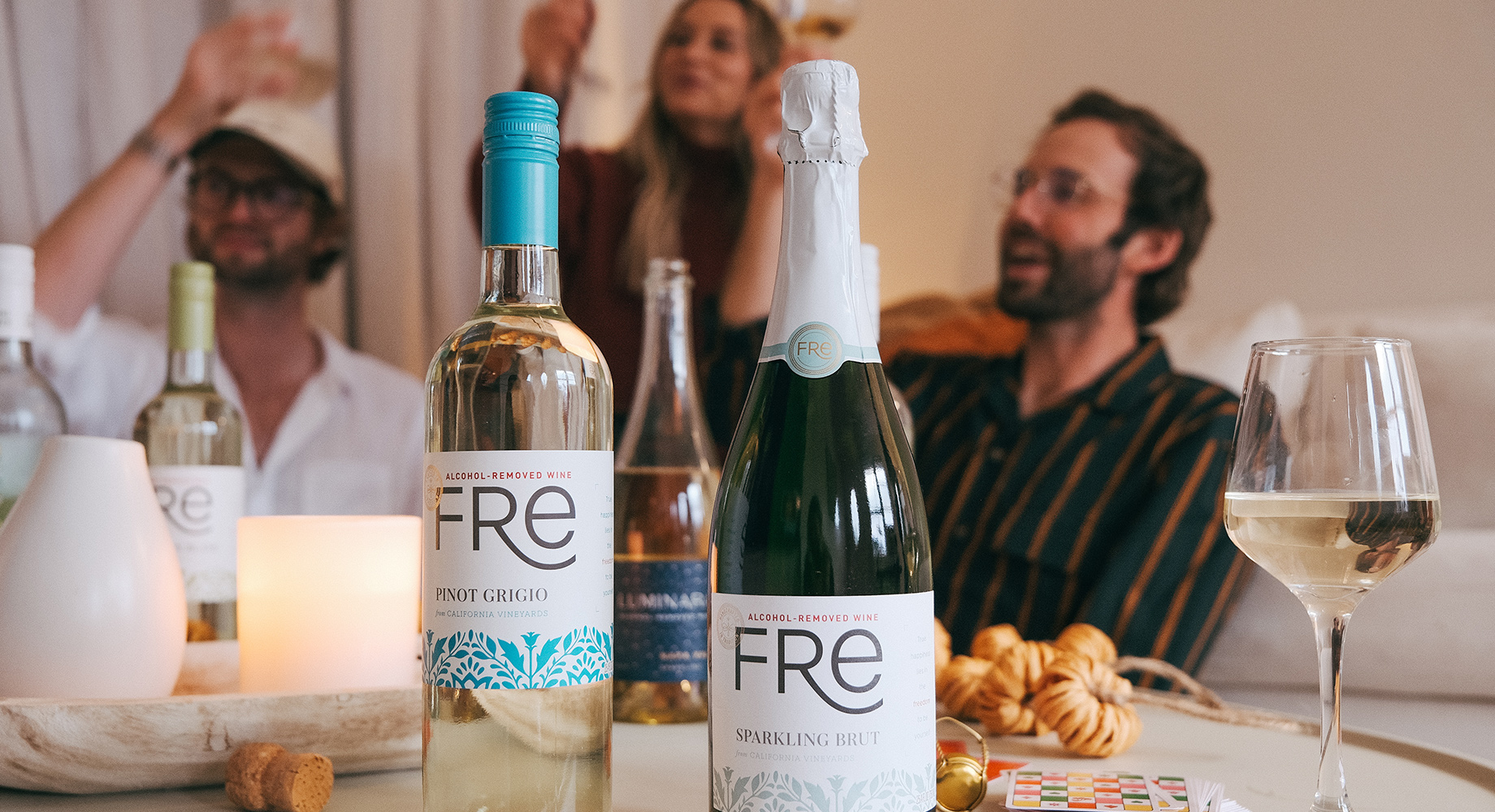 bottles of FRE and Luminara alcohol-removed wines with people raising glasses in the background. Buy these alcohol-removed wines for dry January at One Stop Wine Shop.