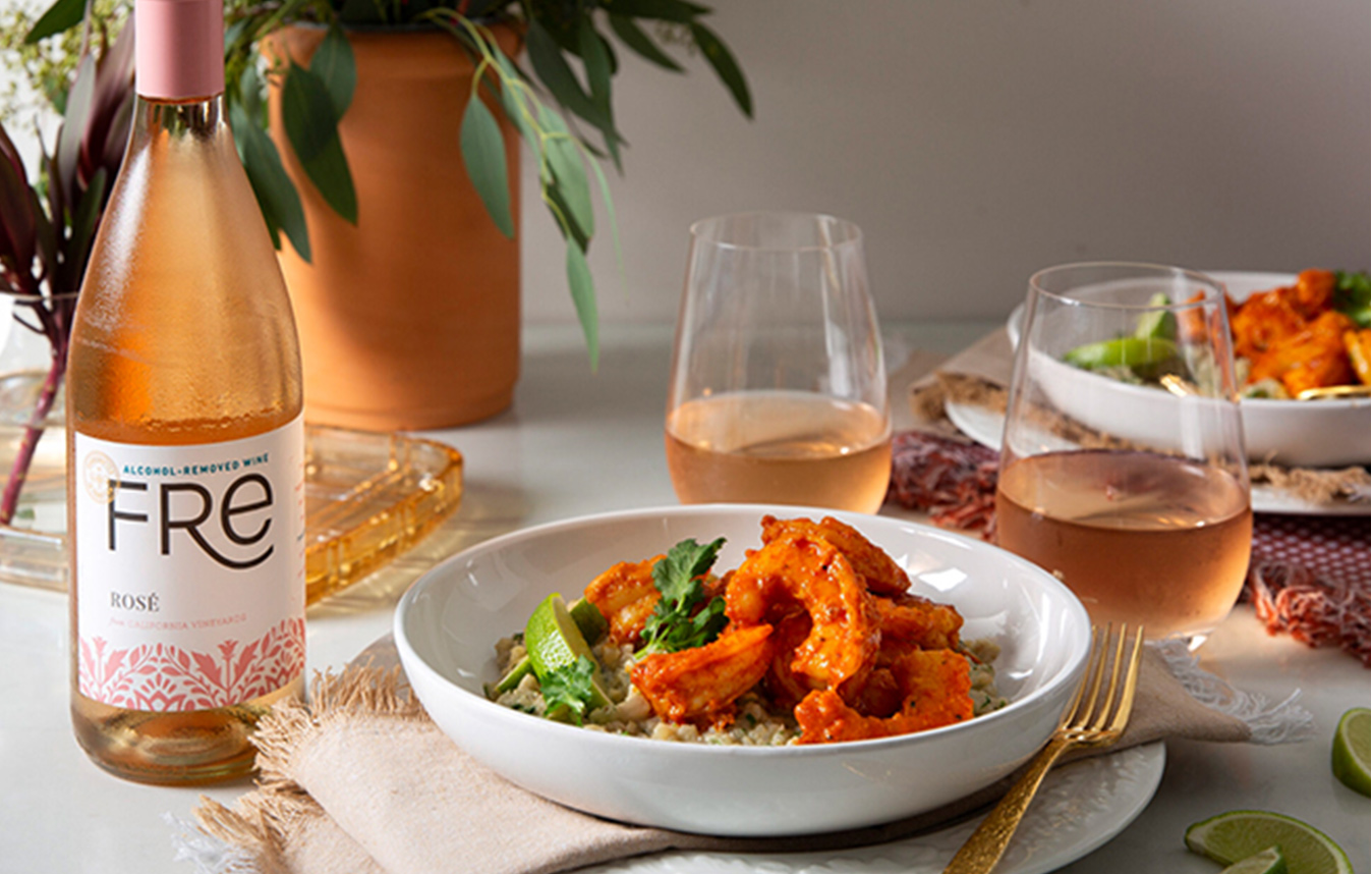 two bowls of red curry shrimp next to two wine glasses and a bottle of FRE alcohol-removed rose. Get this delicious recipe and wine pairing at One Stop Wine Shop.