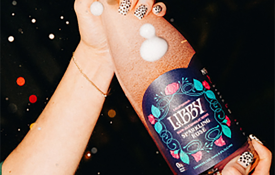 person popping open a bottle of Libby non-alcoholic wine