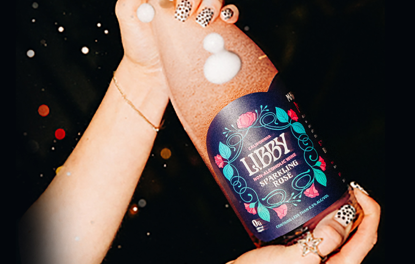 person popping open a bottle of Libby non-alcoholic wine