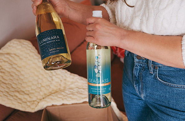 Woman in blue jeans unboxing a One Stop Wine Shop Alcohol-Free Wines & Mixers wine club shipment