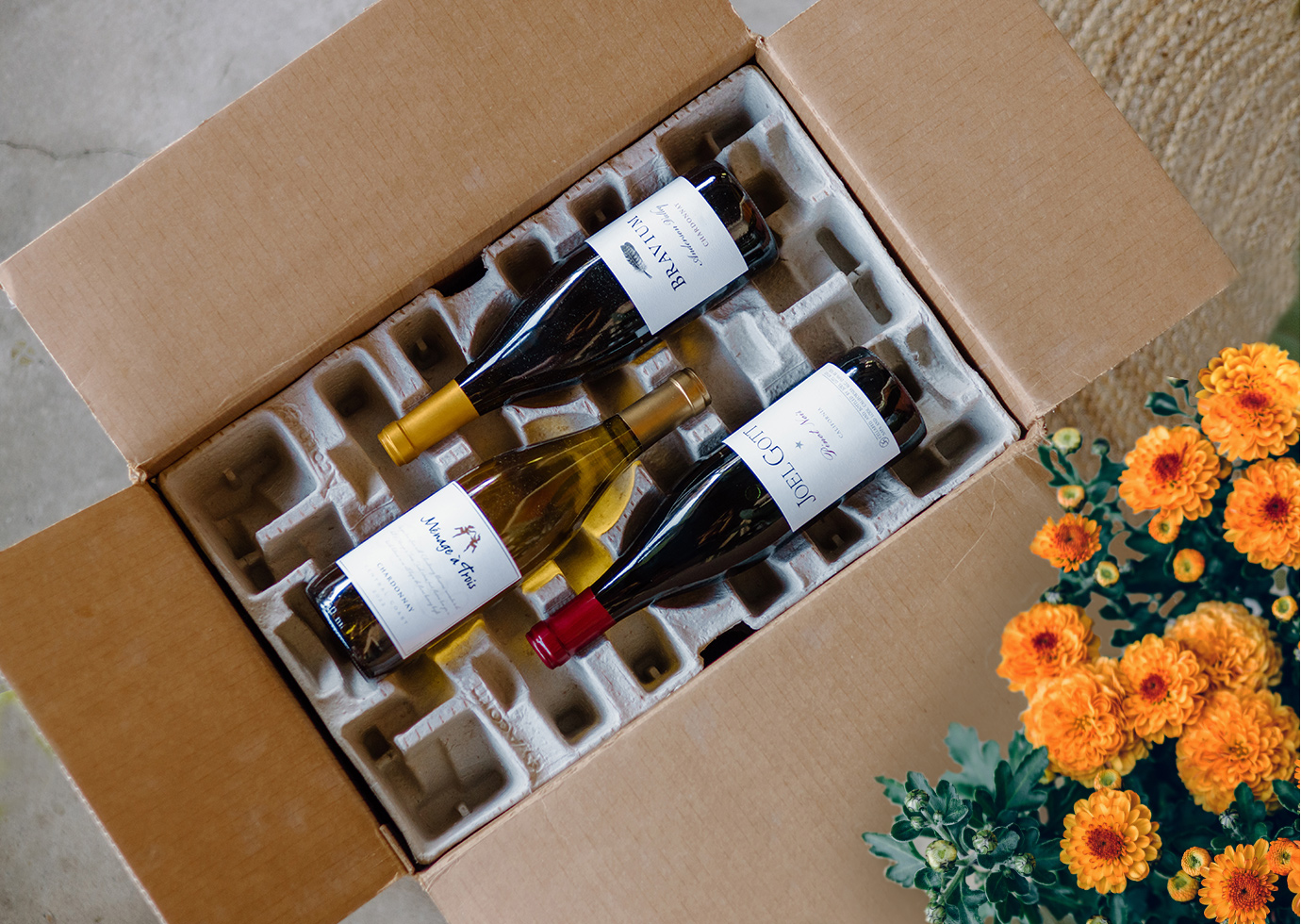 A box of wines from a One Stop Wine Shop everyday wine club shipment next to a bright orange mumm